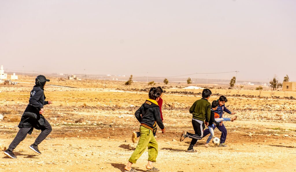 Maheen playing soccer with Syrian children in a Jordanian refugee camp after passing out soccer jerseys she helped fundraise for.