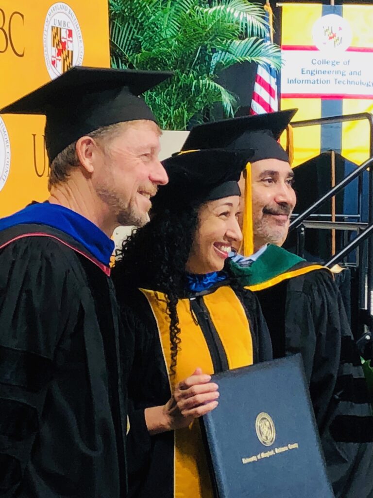 Three people wearing commencement regalia